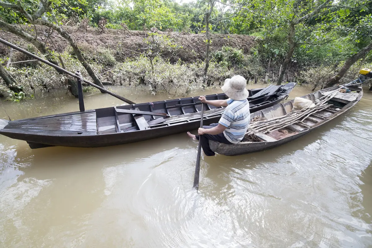 Eine Frau rudert ein Sampan auf einem Mekong-Kanal